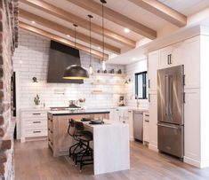 a kitchen with white cabinets and an island in front of the stove, refrigerator and sink