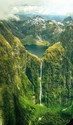 the mountains are covered in green mossy vegetation and there is a small waterfall running down it