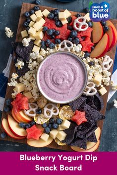 a bowl of fruit, crackers, and other snacks on a cutting board with blueberries