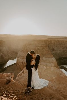 a bride and groom kissing on top of a cliff overlooking the ocean at sunset in iceland