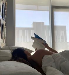 a woman laying in bed reading a book