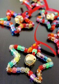 colorful beads and bells on a table with a red ribbon hanging from the end,