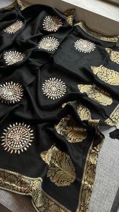 This elegant black saree is crafted from 100% pure Munga silk with intricate Banarasi weaving, featuring a stunning blend of gota patti, zardozi, and pearl work. The exquisite detailing with moti, zardozi, and cutdana adds a sophisticated touch, making it a perfect choice for formal events or festive occasions. Paired with a matching pure Munga silk blouse, this saree embodies timeless craftsmanship and luxury. Fabric of Saree: 100% Pure Munga Silk Banarasi Weaving Work: Gota Patti, Zardozi & Pe Bridesmaids Saree, Lehenga Bridesmaid, Bridesmaid Saree, Pearl Work, Luxury Fabric, Black Saree, Wedding Lehenga, Silk Blouse, Formal Event