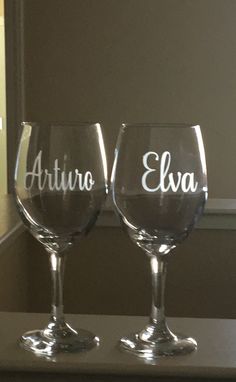 two wine glasses sitting on top of a counter next to each other with the words artino and elva written on them