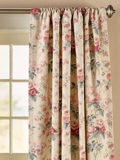 a window with floral curtains hanging on it's side and a curtain rod in front