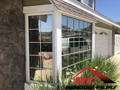 the side of a house that has windows on it and grass in front of it