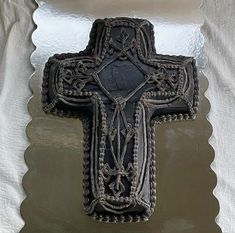 an ornate black cross is hanging on a white wall with scalloped glass panels