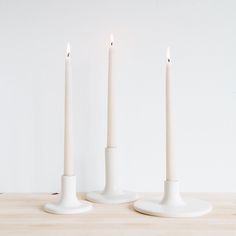 three white candles sitting on top of a wooden table