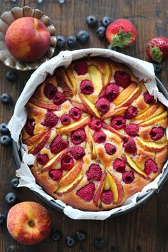 a pie with fresh fruit on top and blueberries around it