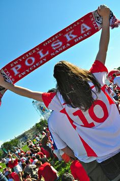 a woman holding up a red and white scarf in front of a crowd at a sporting event