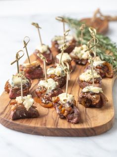 small appetizers are arranged on a wooden platter with toothpicks and cheese