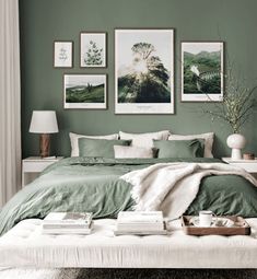 a bedroom with green walls and pictures on the wall above the bed in front of it