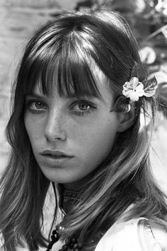 a young woman with long hair and flower in her hair is looking at the camera