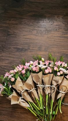 a bunch of flowers that are on top of a wooden table and tied in some kind of paper