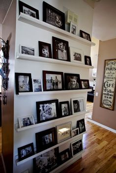 there are many pictures on the shelves in this room and one is framed with black and white photos