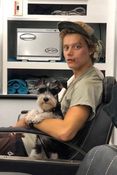 a man sitting in a chair holding a small dog