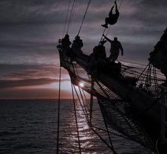 the sun is setting on an old sailing ship