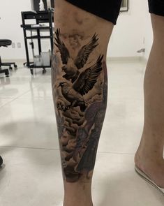 a man's leg with an eagle and clouds tattoo on it