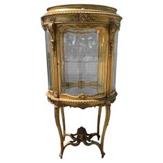 an old fashioned display cabinet with glass doors and gold trimmings on the sides