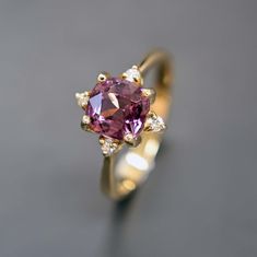 Crafted in 14k yellow gold, this ring features a stunning 1.67 carat natural pink/purple spinel, its soft blush color symbolizing enduring love and affection. Delicate accent 4 diamonds are placed around the center stone, adding a touch of brilliance and fire. This ring is suitable for an unique engagement ring, bridal jewelry, or anniversary gift. ♦ RING SPECIFICATIONS ♦ Solid 14K Yellow Gold Natural Unheated Pink Spinel 1.67 carat Width of the band: 2.0mm The thickness of the band: +/-1.5mm  Ready to ship in 3-5 Business Day after production ♦ CENTER GEMSTONE SPECIFICATIONS ♦ Type: Natural Spinel Shape: Cushion Carat Weight: Approx 1.67 carat Color: Pink/Purple ♦ We only work with high-quality gemstones ♦ The ring comes with our Jewelry certificate which states all of the specifications Pink Spinel, August Birthstone, Big Rings, Gift Ring, Unique Engagement, August Birth Stone, Recycled Gold, Blush Color, Unique Engagement Rings