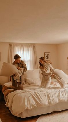 a man and woman sitting on top of a bed in a bedroom next to each other