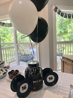 a table topped with black and white balloons next to plates filled with desserts on top of a table