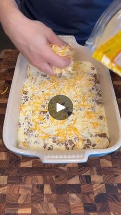 someone adding cheese to a casserole dish