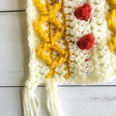 a crocheted white and yellow bag with red buttons on it's side