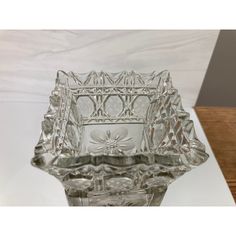 a clear glass bowl sitting on top of a wooden table next to a white wall