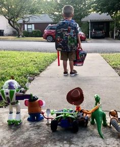 a young boy is walking down the sidewalk with his toys