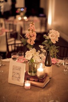 a table topped with books and vases filled with flowers