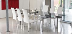 a glass dining table with white chairs in a room