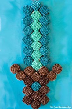 the beaded monkey is hanging on a blue background with brown and green beads in it's mouth