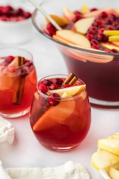 two glasses filled with cranberry apple cider punch on top of a table