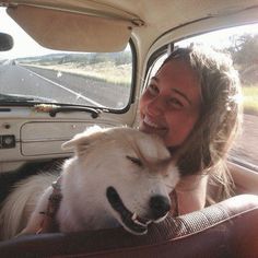 a woman sitting in the back seat of a car with a dog on her lap