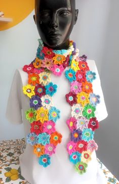 a white mannequin with multicolored crocheted flowers on it's neck