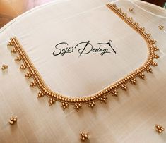 a gold necklace is displayed on a white tablecloth with the words suti's designs written below it