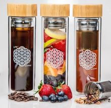 three glass bottles filled with different types of tea and fruit next to each other on a white surface