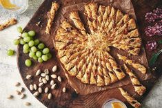 a wooden platter with grapes, nuts and bread