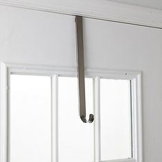 an open window with a handle hanging from it's side in front of white walls