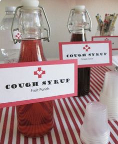 red and white striped table cloth with labels for cough syrup on it, sitting next to two clear plastic cups