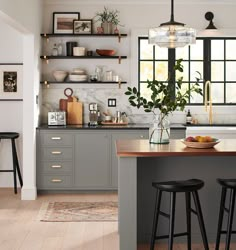 a kitchen with gray cabinets and wooden counter tops, two stools are in front of the island