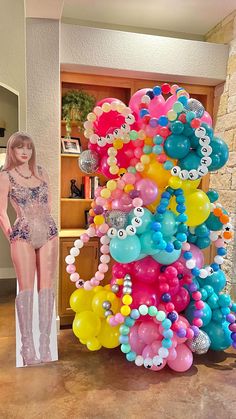 there is a tall balloon tree in the living room with balloons all over it and a woman standing next to it