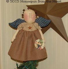 a doll is hanging on the wall next to a christmas tree with a star above it