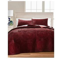 a bed with a red comforter and pillows