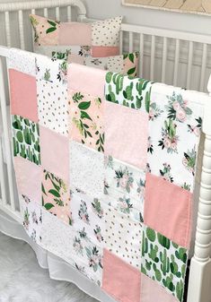 a white crib with a pink and green patchwork quilt