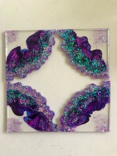 purple and green art work on a white surface with glitters in the middle, as seen from above