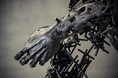 a metal sculpture with hands and nails on it