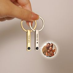 a hand holding a keychain that has a photo on it and two keys attached to it