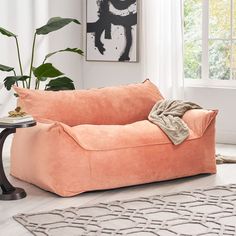 a living room with a large pink couch and rugs on the floor in front of a window